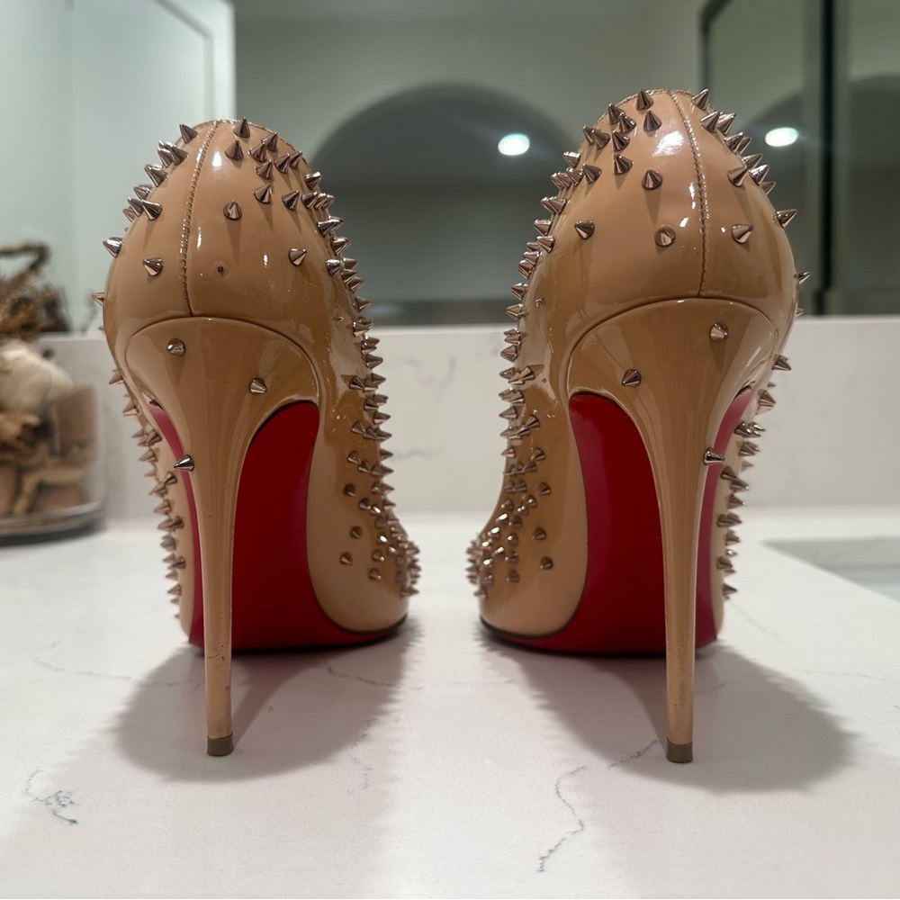 CHRISTIAN LOUBOUTIN
Patent Leather Studded Accents Pumps.